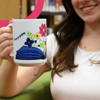 A young woman holding a custom mug.